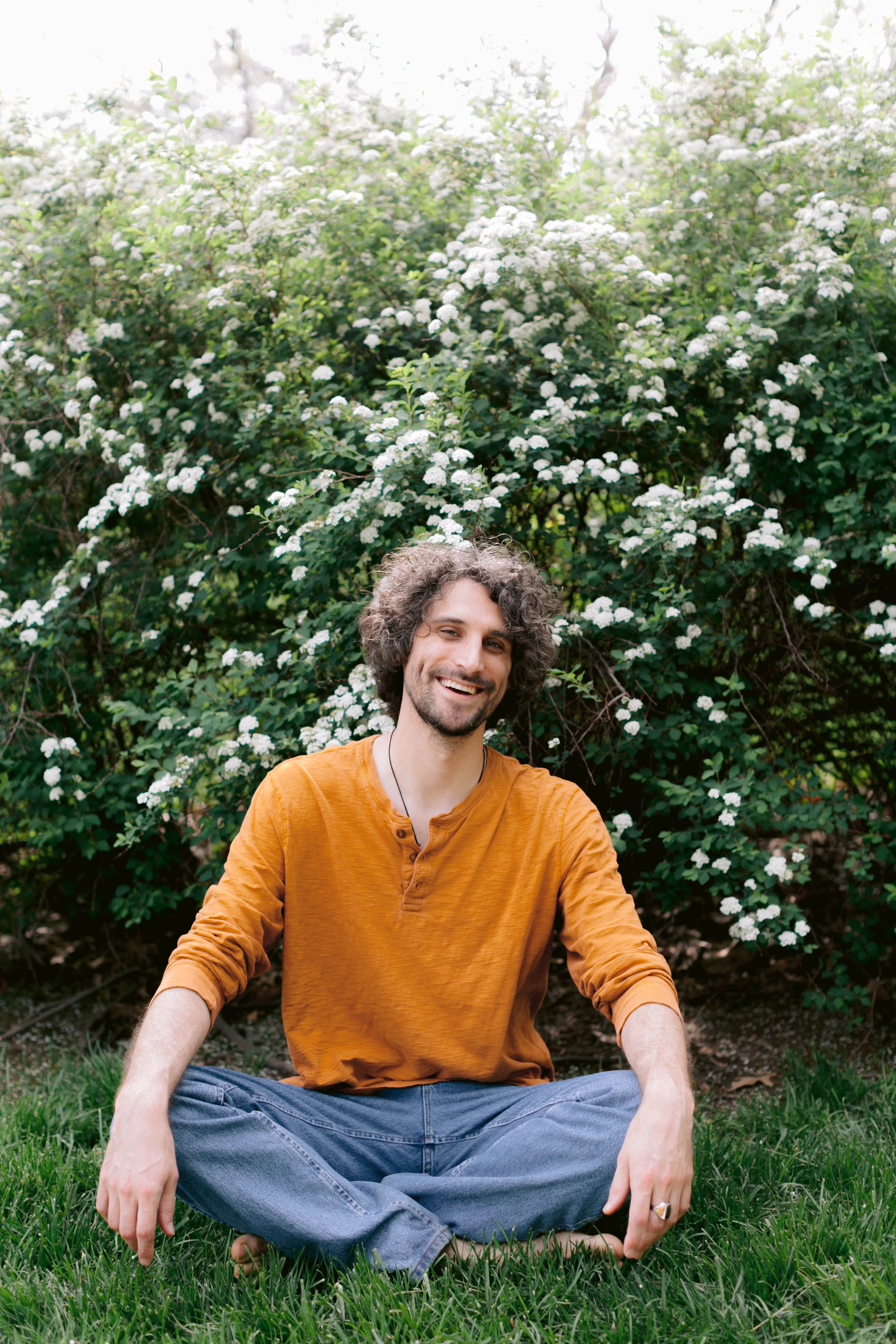 Ross Taylor Williams seated cross-legged in natural setting